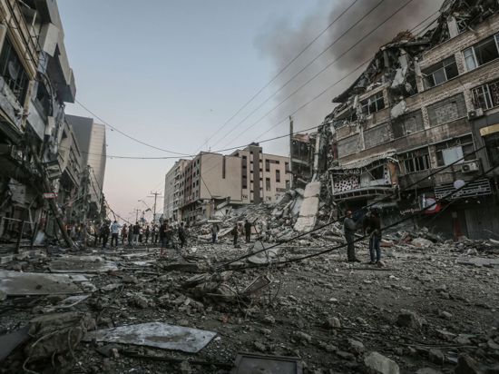 Menschen stehen vor dem eingestürzten Al-Shorouk Tower, nachdem dieser bei einem israelischen Luftangriff getroffen wurde.