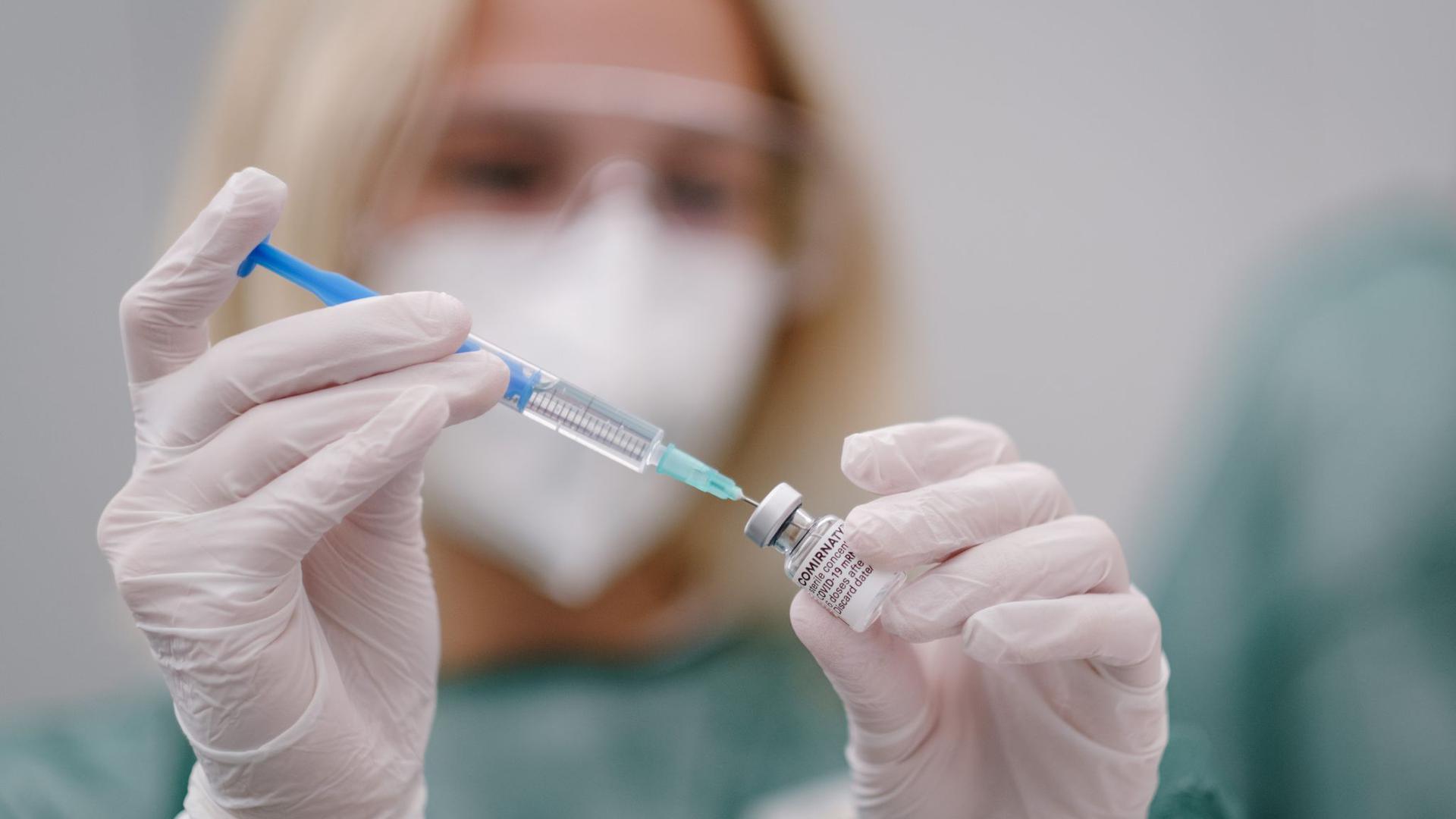 Eine Mitarbeiterin im Gesundheitswesen zieht eine Spritze mit Covid-19-Impfstoff auf.