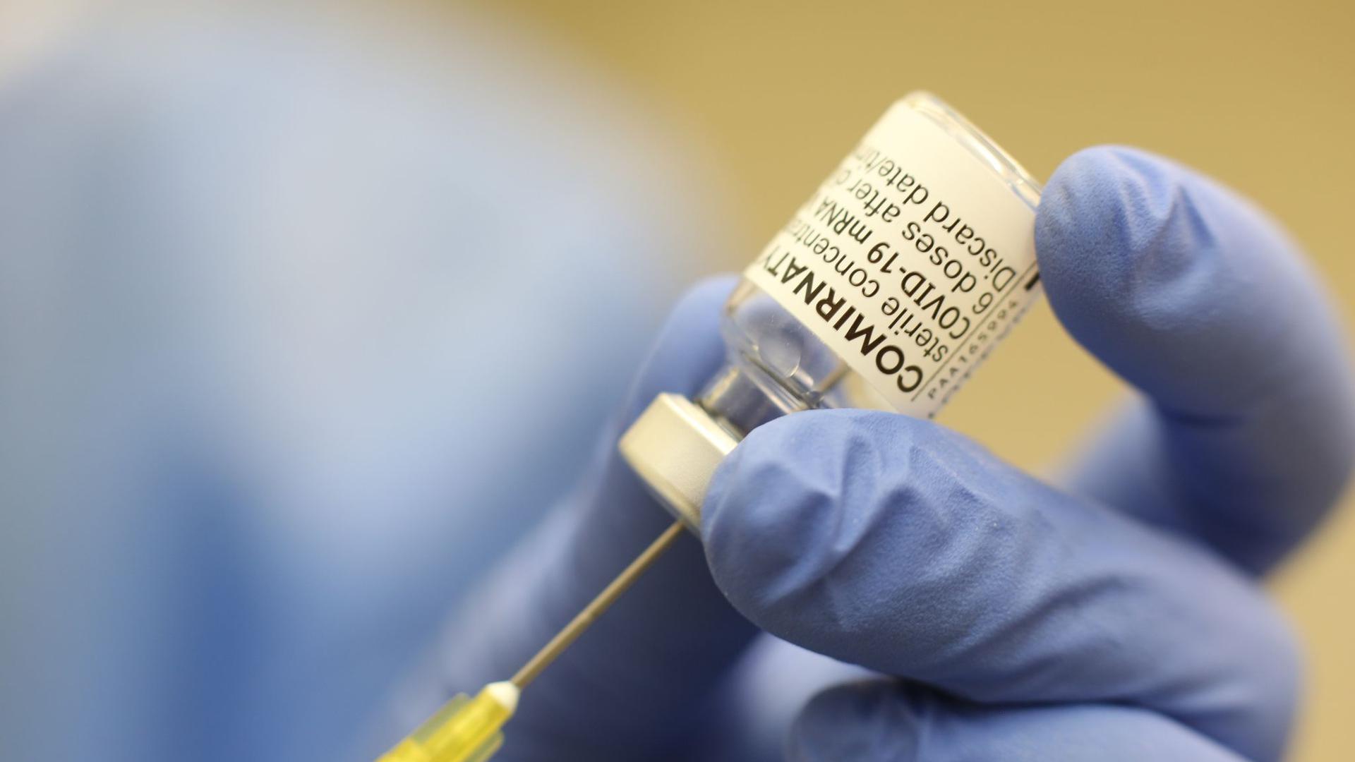 Eine Ärztin zieht eine Spritze mit Impfstoff auf.