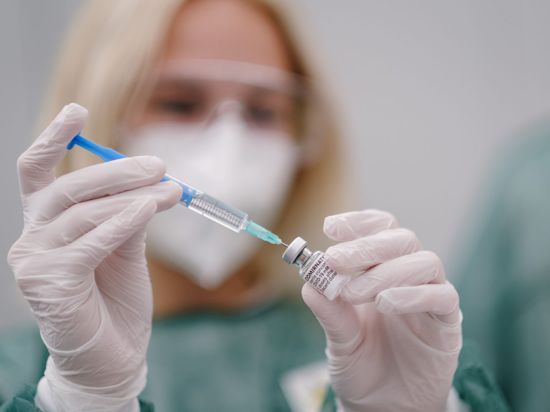 Eine medizinische Mitarbeiterin zieht in einem eine Spritze mit dem Covid-19 Impfstoff Comirnaty des Herstellers BionTech Pfizer auf.
