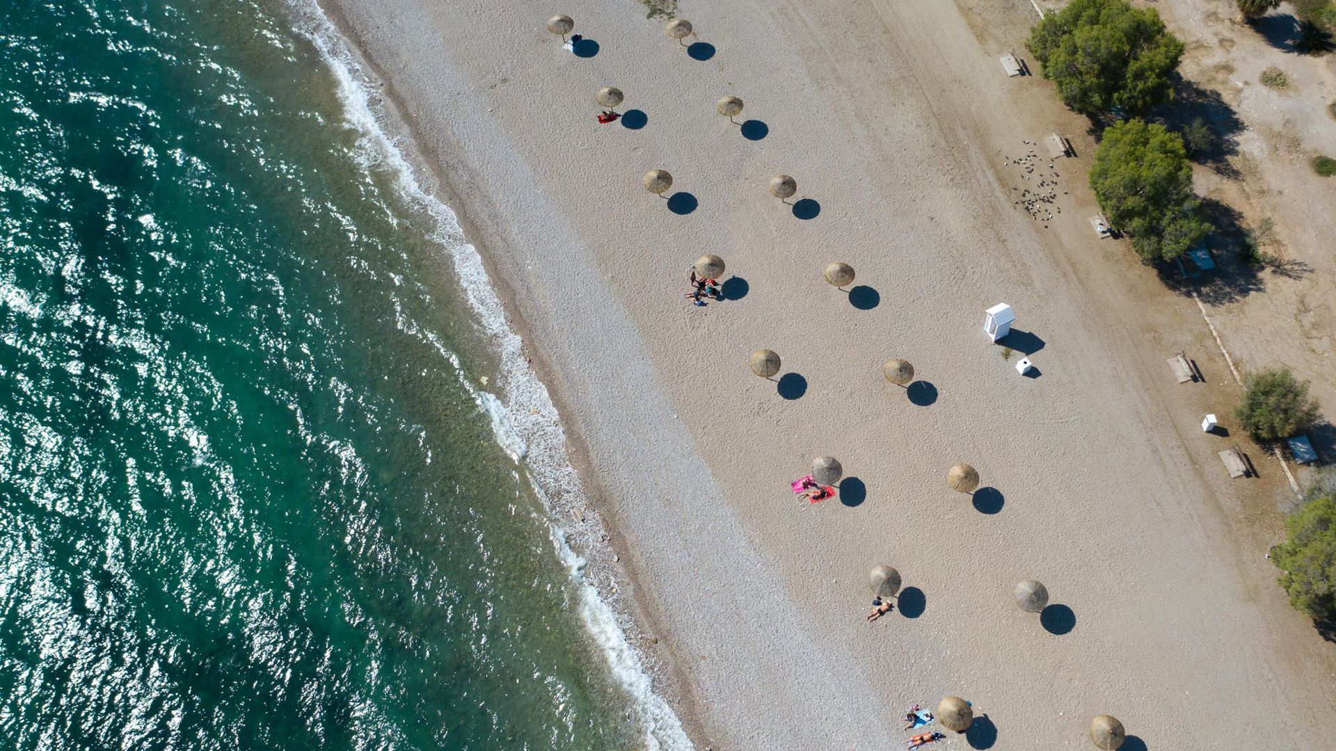 An einem Strand südlich von Athen stehen Sonnenschirme für Strandbesucher bereit. Wegen sinkender Corona-Infektionszahlen streicht die Bundesregierung am Sonntag Griechenland, fast ganz Frankreich, die Schweiz und Belgien von der Liste der Risikogebiete.