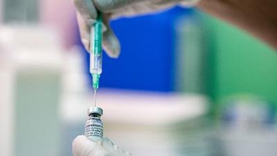 Ein Arzt zieht den Corona-Impfstoff Comirnaty von Biontech/Pfizer in eine Spritze.