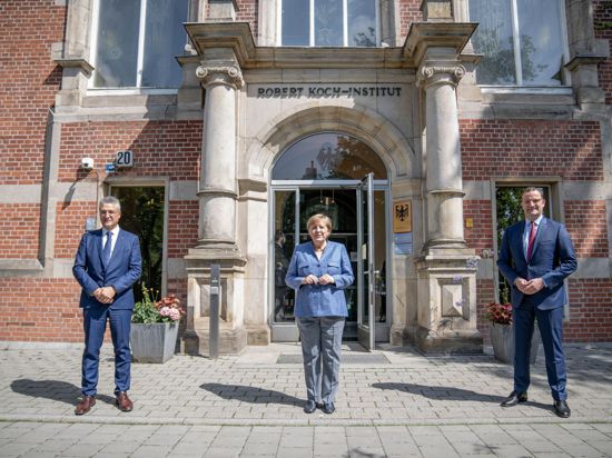 RKI-Präsident Lothar Wieler, Bundeskanzlerin Angela Merkel und Bundesgesundheitsminister Jens Spahn vor dem Eingang zum Robert Koch-Institut.