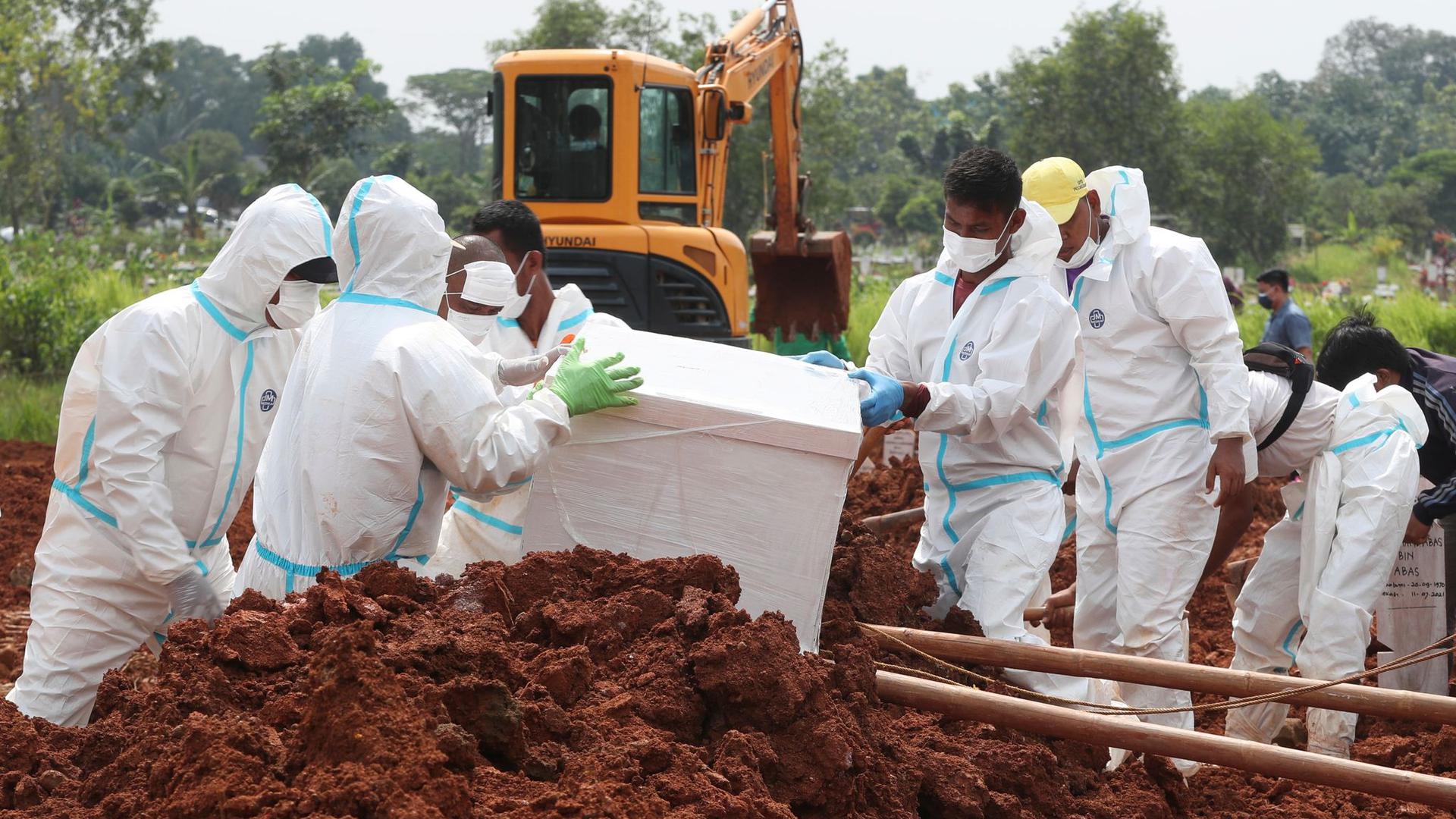 Arbeiter bereiten einen Sarg für eine Beerdigung auf dem speziellen Corona-Abschnitt eines Friedhofs in Indonesien vor.