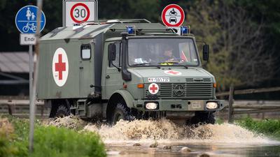 Ein Sanitätsfahrzeug der Bundeswehr fährt über eine überflutete Straße.