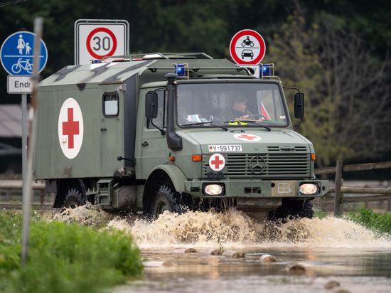 Ein Sanitätsfahrzeug der Bundeswehr fährt über eine überflutete Straße.