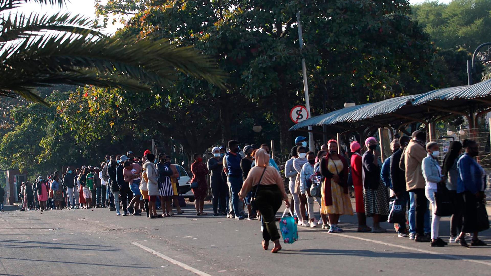 Menschen stehen in Durban vor einem Einkaufszentrum Schlange, um sich mit dem Nötigsten zu versorgen.