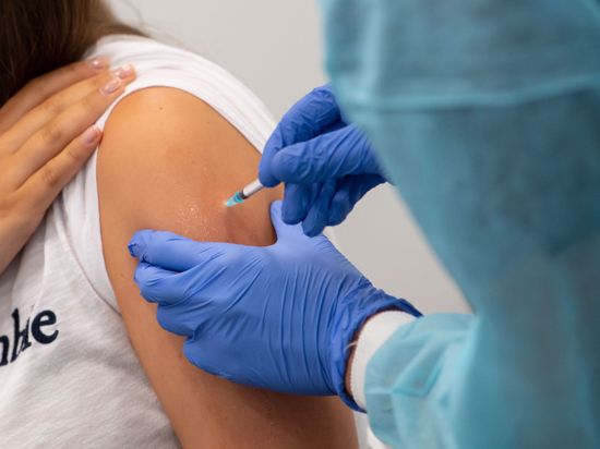 Eine Frau bekommt in einem Impfzentrum eine Corona-Impfung verabreicht.