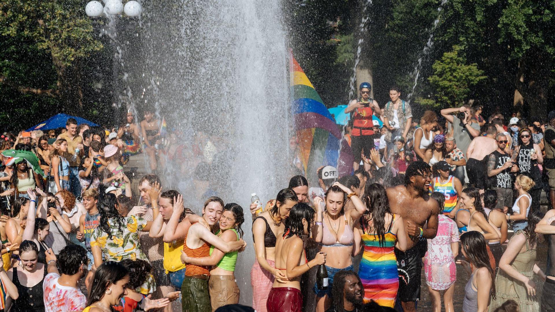 Junge Leute feiern während der Pride Parade im kühlen Nass des Brunnens am Washington Square Park in Manhattan.