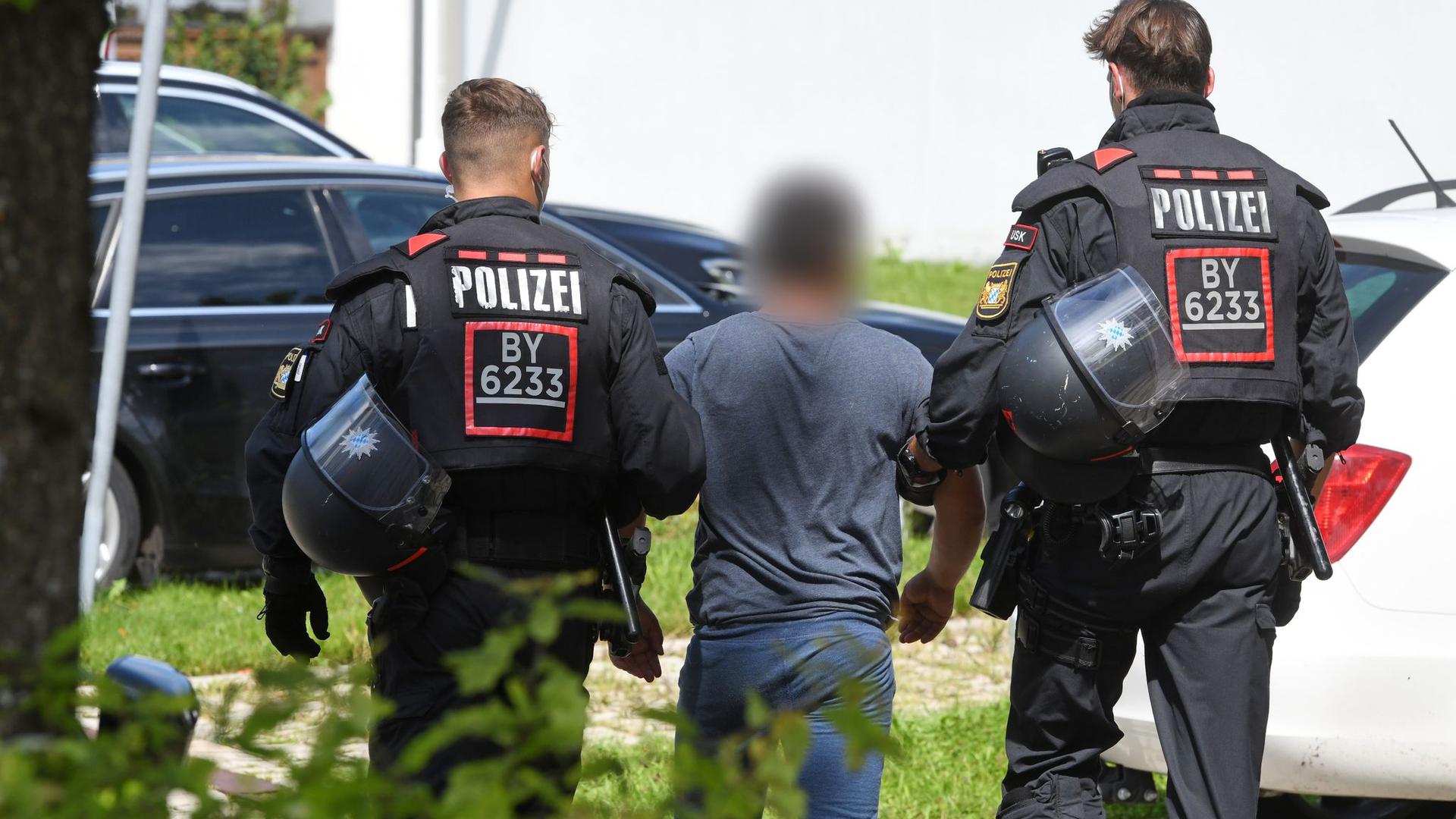 Zwei Einsatzkräfte der Polizei führen in Miesbach einen Tatverdächtigen ab.