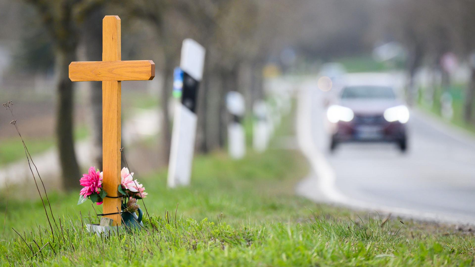 Ein Kreuz zum Gedenken an ein Opfer eines Verkehrsunfalls steht an einer Landstraße.