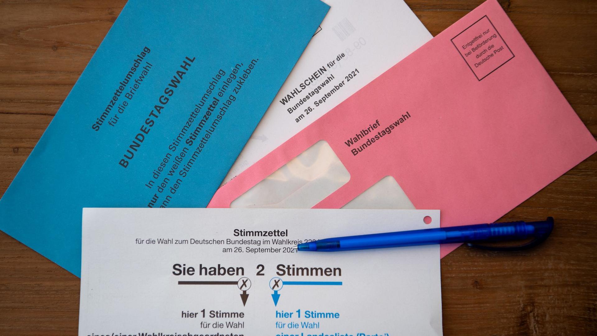 Briefwahlunterlagen für die Bundestagswahl 2021 mit Stimmzettel und Stimmzettelumschlag liegen auf einem Tisch.