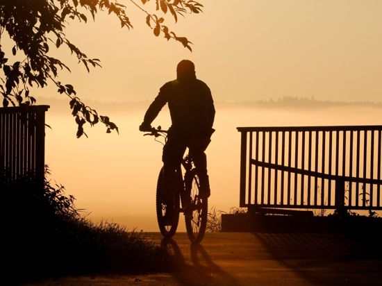 Ein Radfahrer fährt bei Sonnenaufgang über eine Brücke.