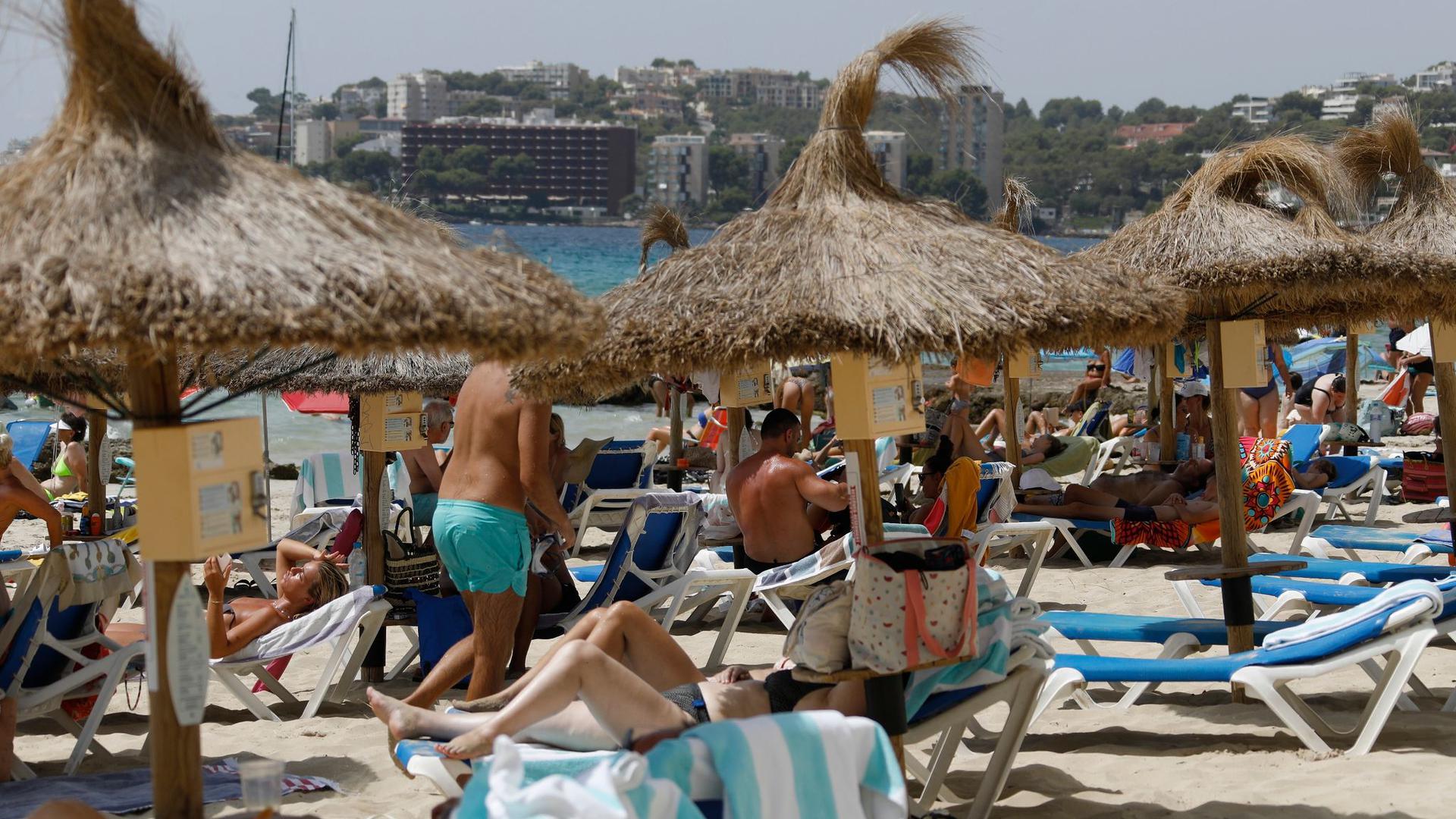 Einheimische und Touristen liegen am Strand Cala Major in Palma de Mallorca.