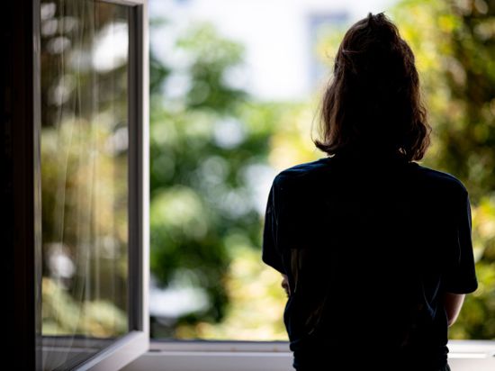 Eine Frau steht in ihrer Wohnung an einem Fenster. (Archivbild)