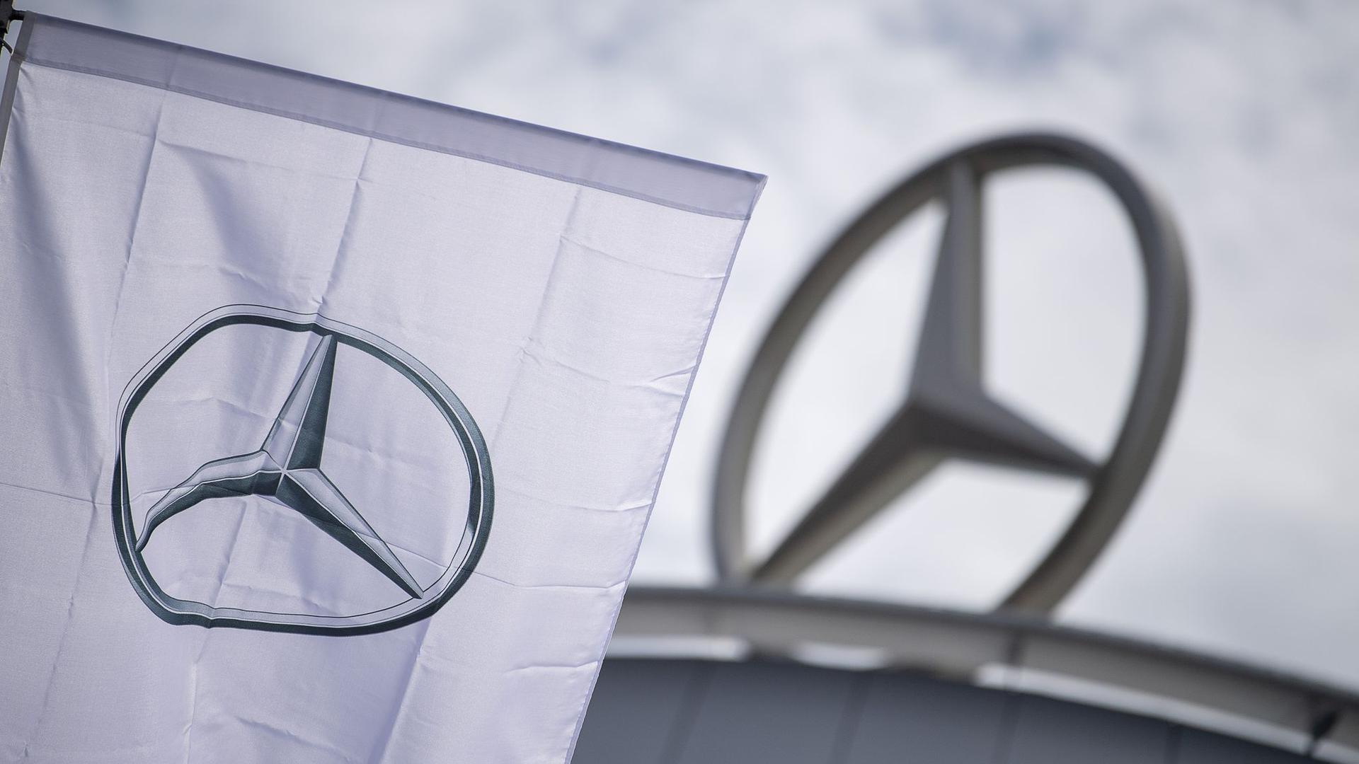 Eine Fahne mit dem Logo der Marke Mercedes-Benz weht vor einem Showroom der Firma.