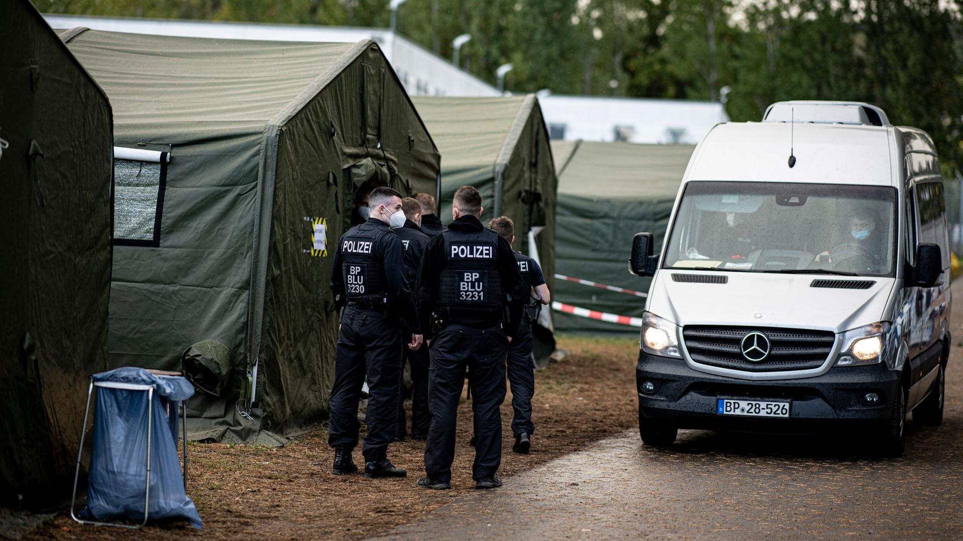 Polizisten in der Erstaufnahmeeinrichtung Eisenhüttenstadt neben einem Zelt für neu ankommende Asylsuchende.