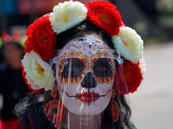 Eine als „Catrina“ verkleidete Frau trägt während der Feierlichkeiten zum Tag der Toten ein Gesichtsschild. Der Día de Muertos in Mexiko ehrt verstorbene Angehörige.