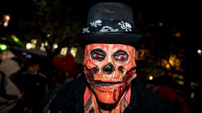 Ein Mann mit einer Totenkopf-Maske und glühenden roten Augen bei der Essener Halloween-Parade. Neben fantasievollen Kostümen gab es in der Nacht in Teilen Deutschlands auch Ruhestörungen, Böllerwürfe und Ausschreitungen.