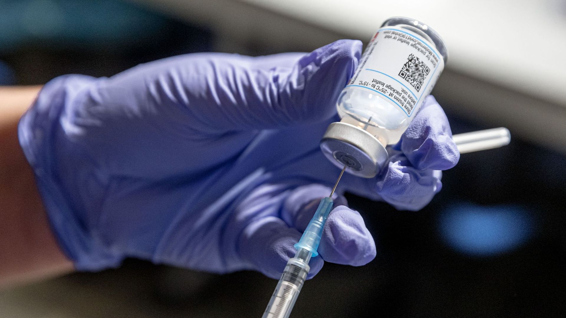 Eine Krankenschwester zieht Corona-Impfstoff aus einer Ampulle in eine Spritze auf.