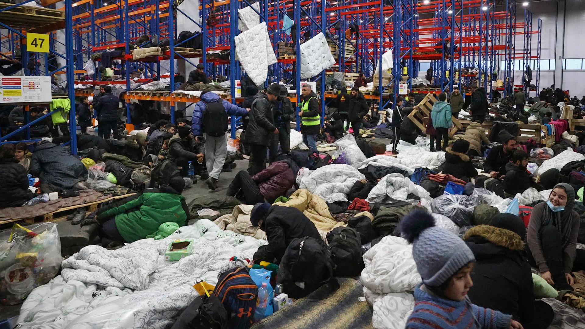 Migranten, die sich für die Nacht im Logistikzentrum am Kontrollpunkt „Kuznica“ an der belarussisch-polnischen Grenze einrichten.