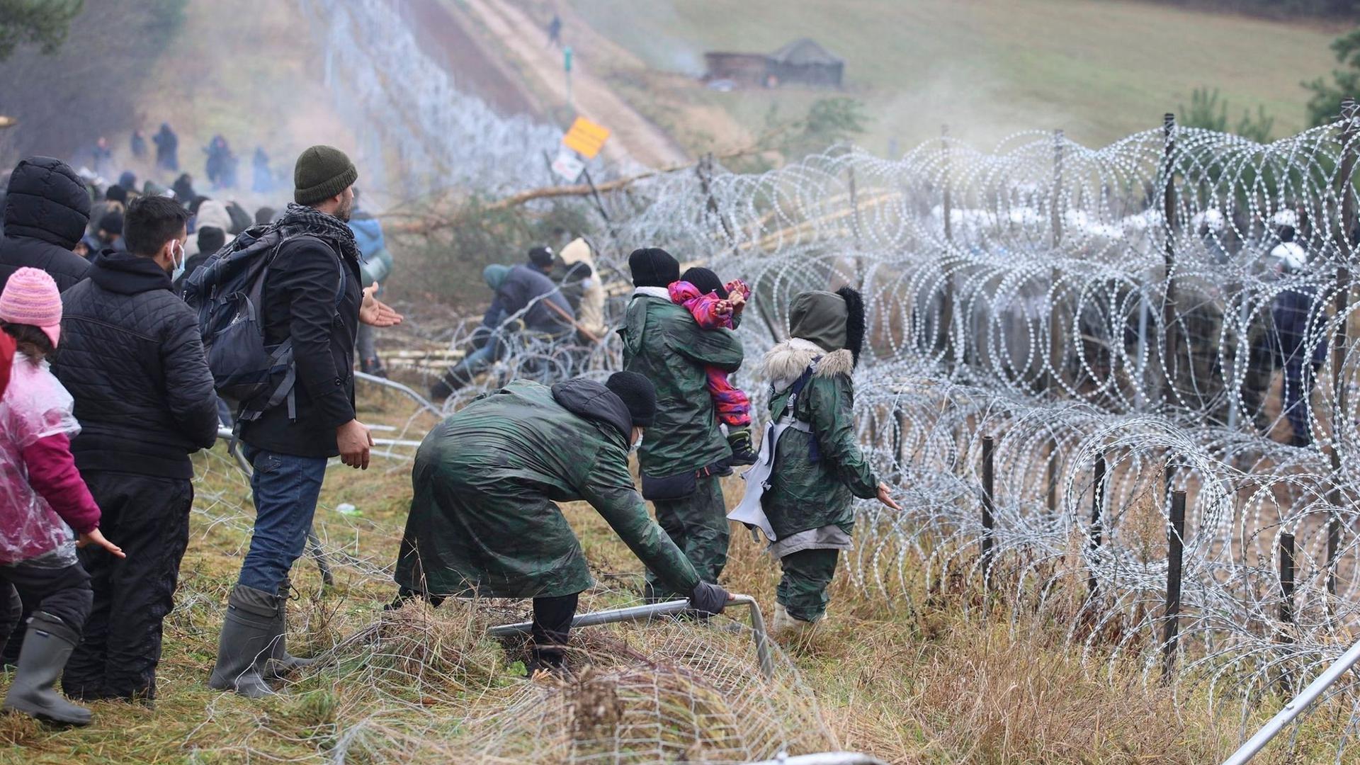 Getrennt durch Stacheldraht: Migranten stehen an der Grenze auf der belarussischen Seite – auf der polnischen stehen Sicherheitskräfte.