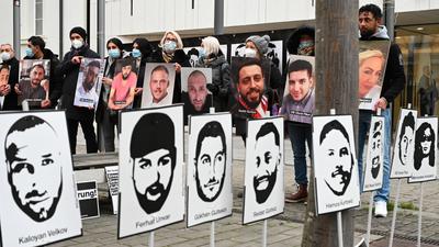Angehörige der Opfer des rassistischen Anschlags von Hanau 2020 halten bei einer Mahnwache vor dem hessischen Landtag Fotos der Opfer.
