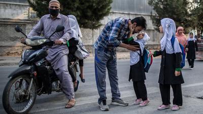 Ein junges afghanisches Mädchen gibt ihrem Vater einen Kuss, bevor sie eine Grundschule in Kabul besucht. (Archivbild)