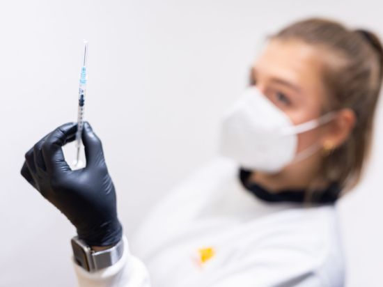 Die Mitarbeiterin eines Impfzentrums hält eine Spritze mit einem Impfstoff gegen Corona in der Hand.