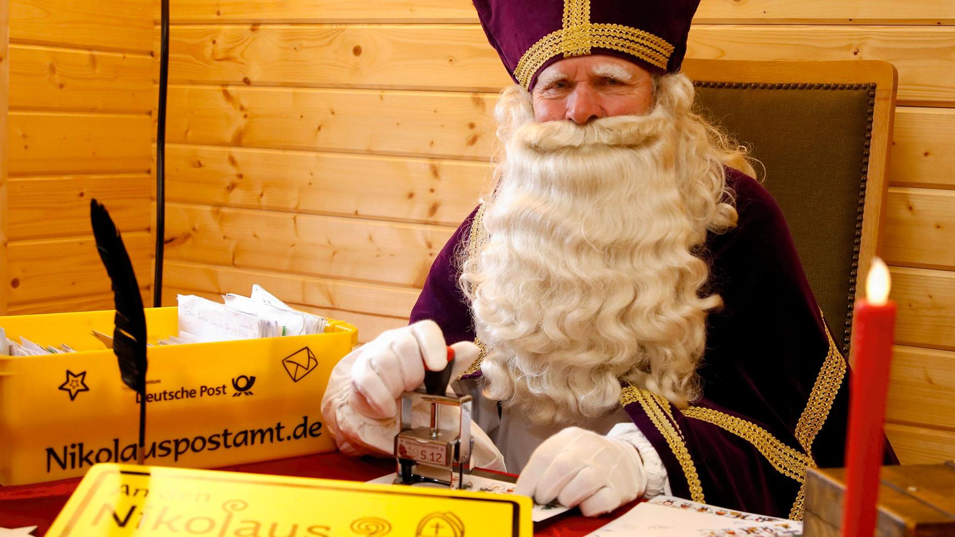 Ein Nikolaus sitzt in seiner Nikolaushütte des Nikolauspostamtes in St. Nikolaus und beantwortet Briefe.