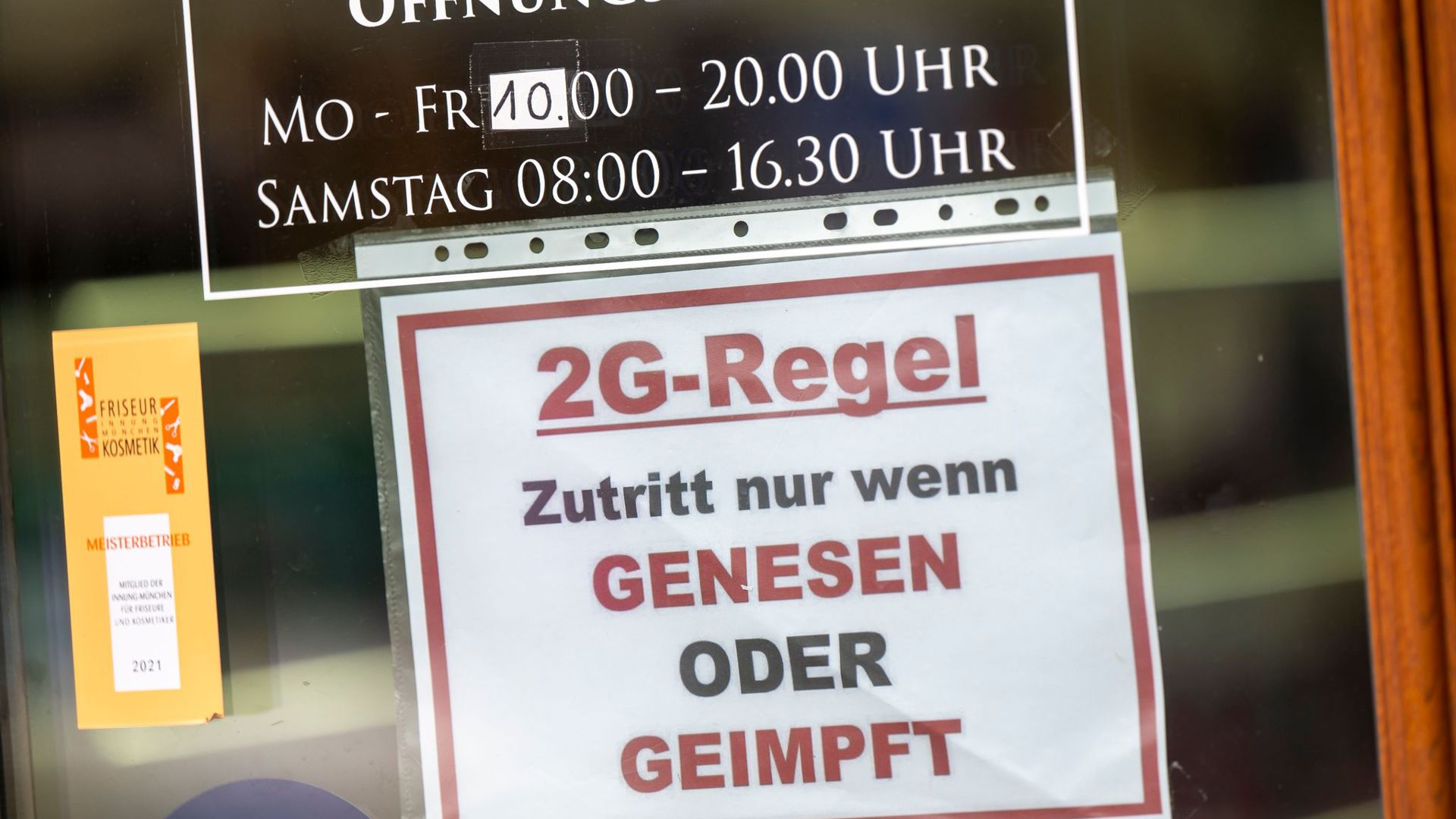 Ein Schild zur „2G-Regel“ hängt an der Eingangstür eines Münchner Friseurladens.