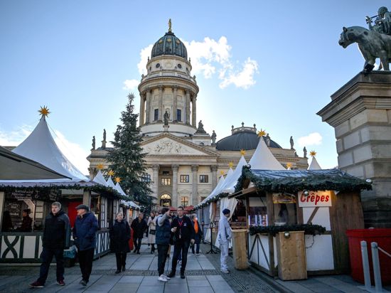 Besucherinnen und Besucher gehen über den Weihnachtsmarkt.