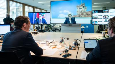 NRW-Ministerpräsident Hendrik Wüst (l.), während der Videokonferenz. Auf dem großen Bildschirm ist Berlins Regierende Bürgermeisterin Franziska zugeschaltet.