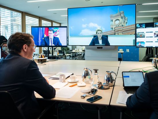 NRW-Ministerpräsident Hendrik Wüst (l.), während der Videokonferenz. Auf dem großen Bildschirm ist Berlins Regierende Bürgermeisterin Franziska zugeschaltet.