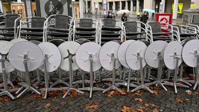 Zusammengestellte Stühle und Tische stehen vor einem Café in München.
