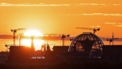 Baukräne und die Kuppel des Reichstagsgebäudes in Berlin. Die deutsche Wirtschaft kommt wieder in Schwung.