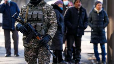 Ein kasachischer Soldat patrouilliert in Almaty nahe einer Polizeistation. Hinter ihm versammeln sich Angehörige von Personen, die nach den Protesten gegen die Regierung verhaftet wurden.