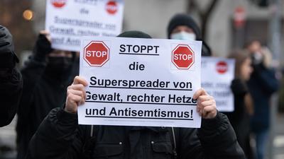 Gegendemonstranten halten am Rande einer Aktion von Gegnern der Corona-Maßnahmen in Frankfurt am Main ein Schild in der Hand. (Archivbild)