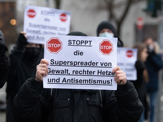 Gegendemonstranten halten am Rande einer Aktion von Gegnern der Corona-Maßnahmen in Frankfurt am Main ein Schild in der Hand. (Archivbild)
