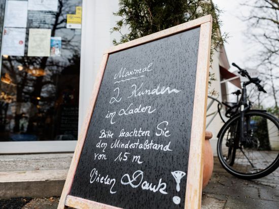 Eine Tafel vor einem Münchener Geschäft weist auf die Maximalanzahl von 2 Personen im Laden hin.