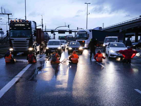 Klimaaktivisten der Aktion „Aufstand der letzten Generation“ blockierten am Montagmorgen in Hamburg eine Kreuzung am Zollamt Waltershof zur Köhlbrandbrücke und zur Autobahn A7.