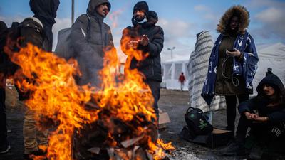 Mehrere Menschen wärmen sich an einem Feuer am Grenzübergang zwischen Polen und der Ukraine.