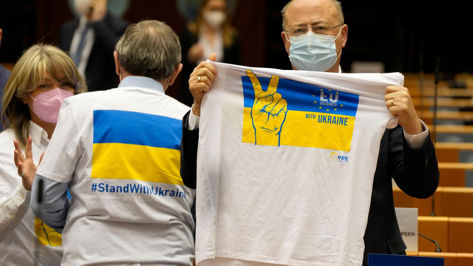 Ein Mitglied des Europäischen Parlaments hält ein T-Shirt in den Farben Blau und Gelb zur Unterstützung der Ukraine.