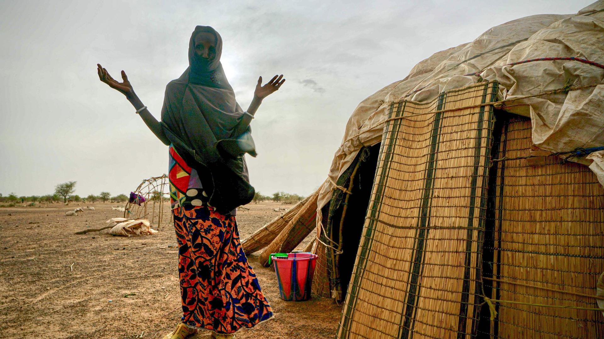 Eine Frau steht neben ihrer Hütte in einer von den Vereinten Nationen unterstützten Siedlung für Binnenflüchtlinge in Burkina Faso.
