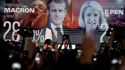 Ein Bildschirm in Paris zeigt den französischen Präsidenten Macron und die rechtsextreme Kandidatin Le Pen am Wahltag. Die beiden kämpfen in einer Stichwahl am 24. April um das höchste Amt im Land.