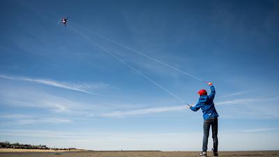 Ein Junge lässt bei schönem Wetter seinen Flugdrachen am Nordseestrand von Cuxhaven fliegen.