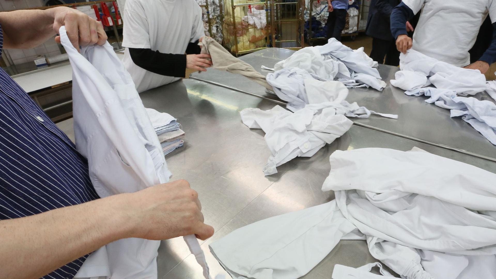 Gefangene der Justizvollzugsanstalt Plötzensee legen in der Wäscherei Wäsche zusammen.