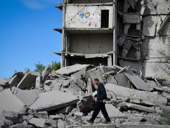 Ein Anwohner geht an einem durch russischen Beschuss zerstörten Haus vorbei.