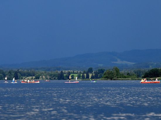 Ausflügler auf dem Wasser flüchten vor einer herannahenden Gewitterfront über dem Staffelsee in Bayern.
