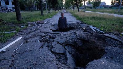 Viktor Schewtschenko steht in einem Krater, der bei einem russischen Angriff auf den Stadtteil Saltiwka in Charkiw entstanden ist.
